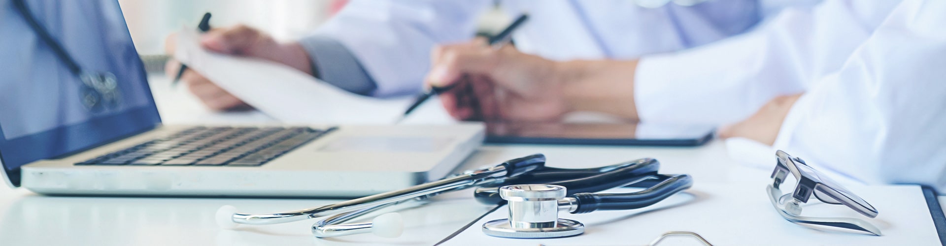 Closeup of laptop and stethoscope on a desk