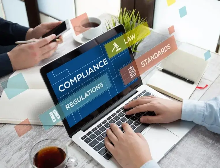 Laptop with hands typing compliance, regulations, and law.