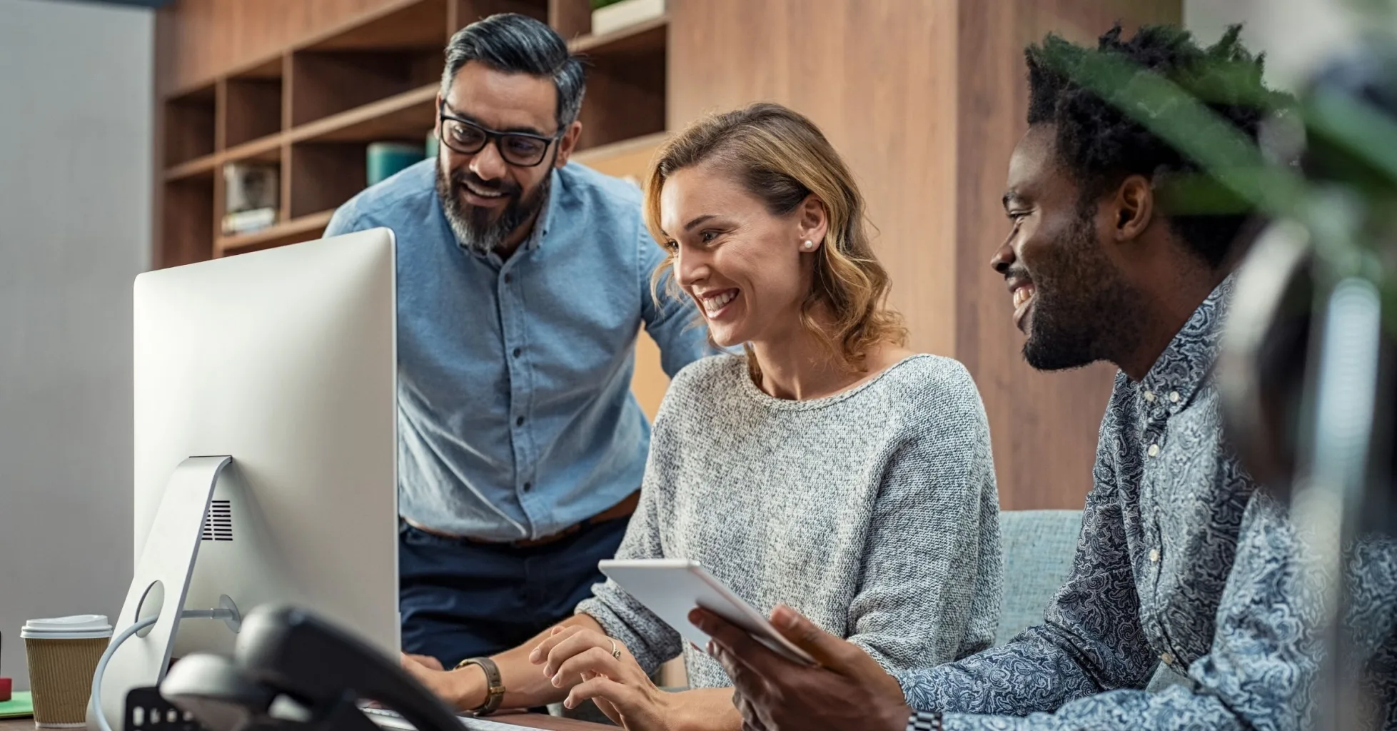 Business professionals collaborating around a desktop computer and tablet.